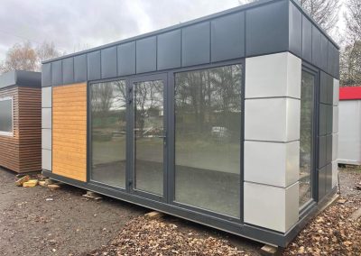 Portable Office with wooden cladding 600cm x 300cm (10ft x20ft) – Model 3 – Steel frame 80x80x3 mm; Galvanized steel; Roof, walls and floor insulated with 100mm Styrofoam; Aluminum double glazed: door, PVC opening window and 2 PVC fix windows;